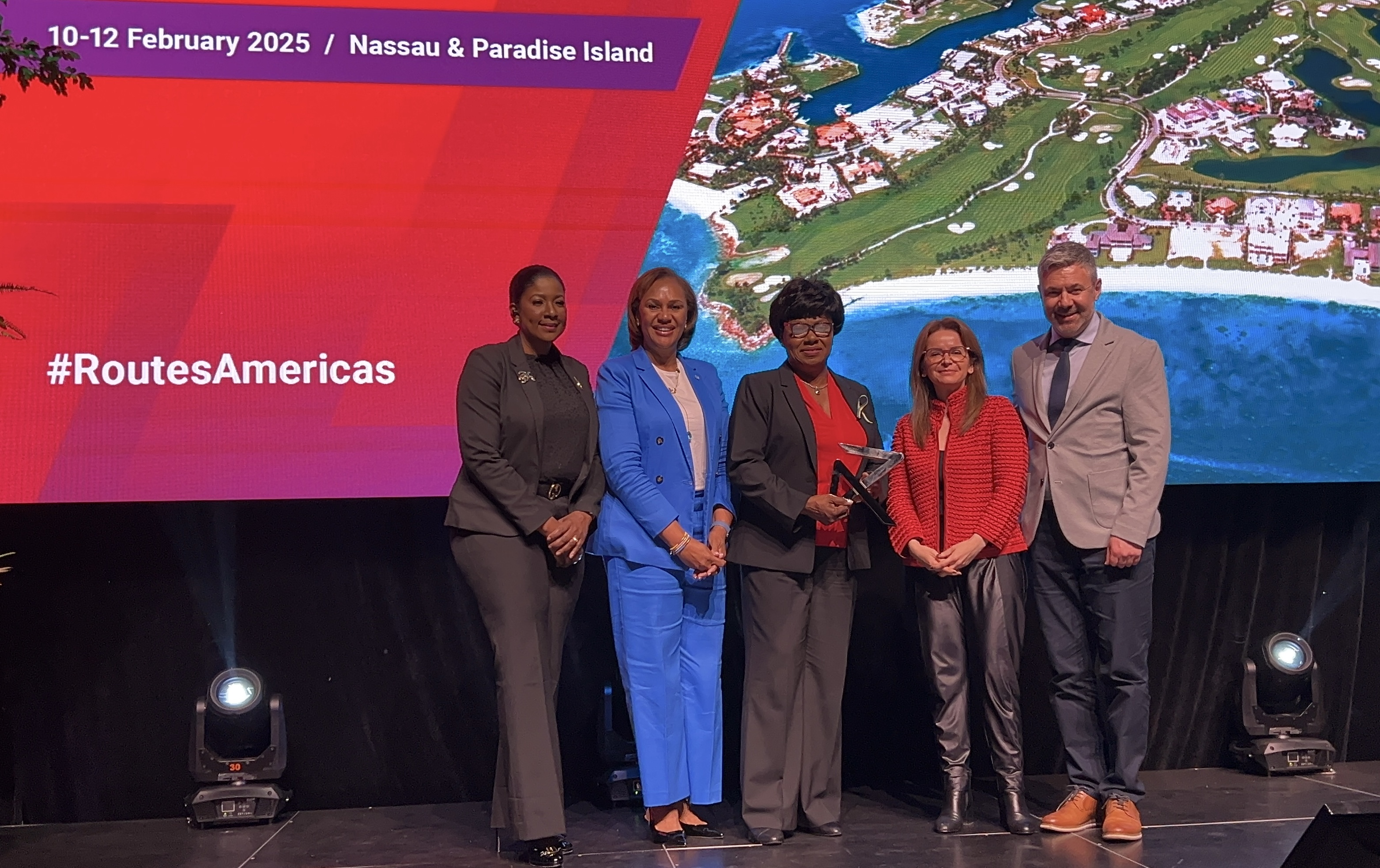 Latia Duncombe, Director General, Bahamas Ministry of Tourism, Joy Jibrilu, CEO of Nassau Paradise Island Promotion and Vernice Walkine, President & CEO, Nassau Airport Development Company accept the handover trophy as the official destination of Routes America 2025