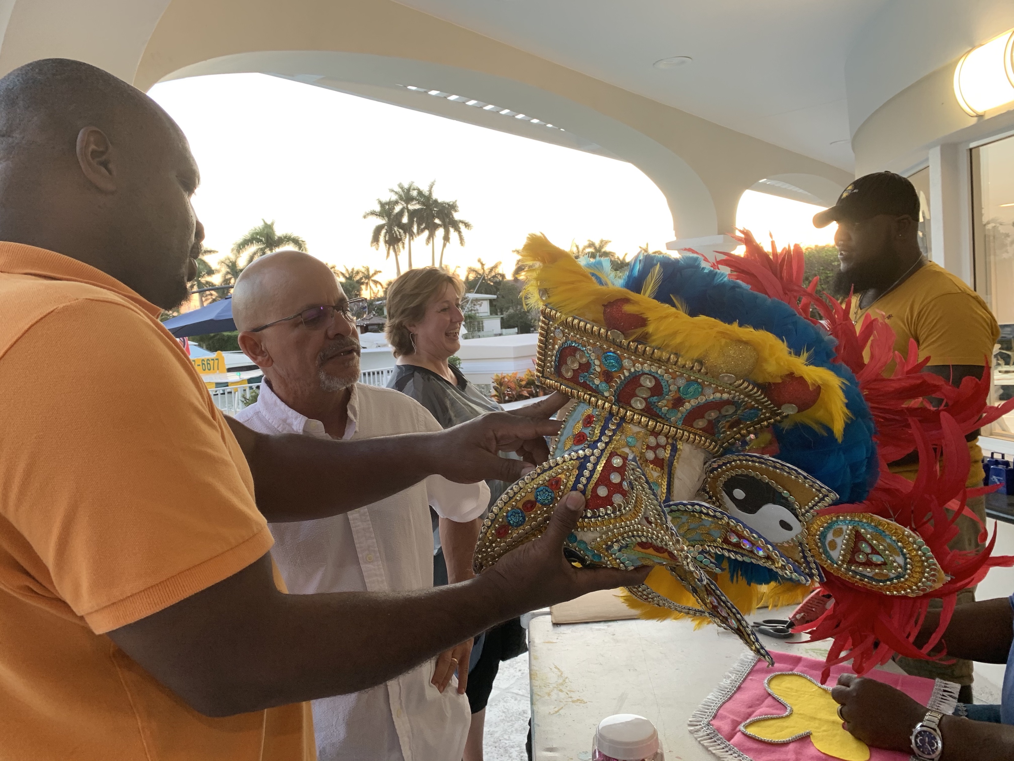 Vernon Brooks of Sunshine Junkanoo Band, (L) describes the artwork on a Junkanoo headpiece to an attendee.