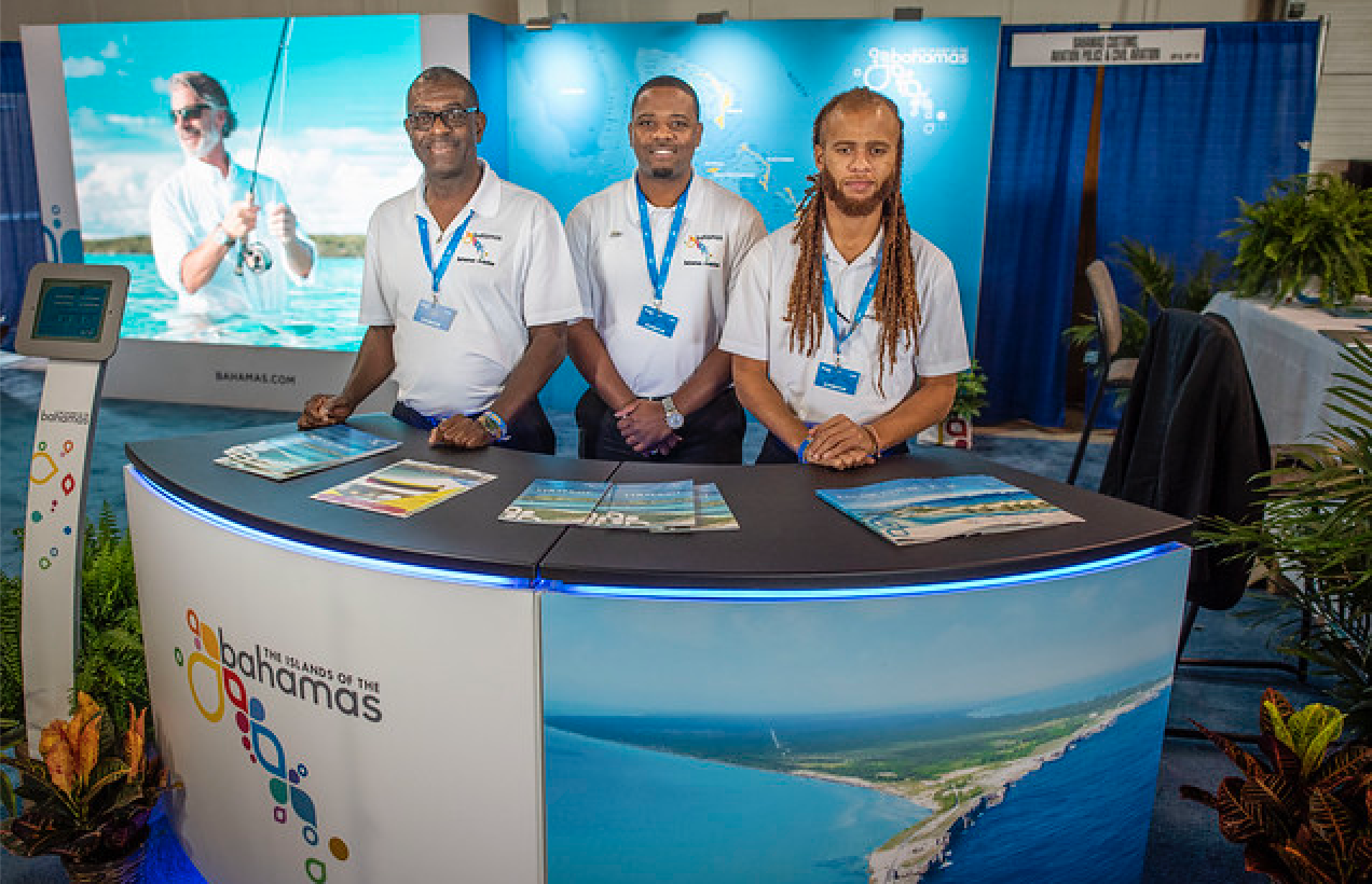 1.	Pictured are staff members of the Bahamas Ministry of Tourism and Aviation standing ready at its booth to answer aviators’ questions, prior to EAA AirVenture Oshkosh gate opening.  From left to right are Leonard Stuart, Ahmad Williams and Aram Bethell.